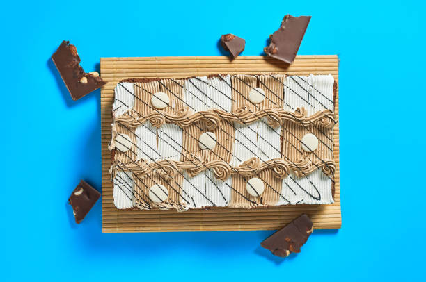 istock One whole checkered rectangular cake on bamboo mat near broken chocolate bar with nuts lies on blue table on party. Celebration concept. Top view. Close-up 1200594364