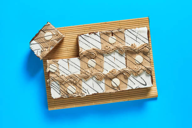 istock Sliced checkered rectangular cake on bamboo mat lies on blue table on party. Celebration concept. Top view. Close-up 1200594411
