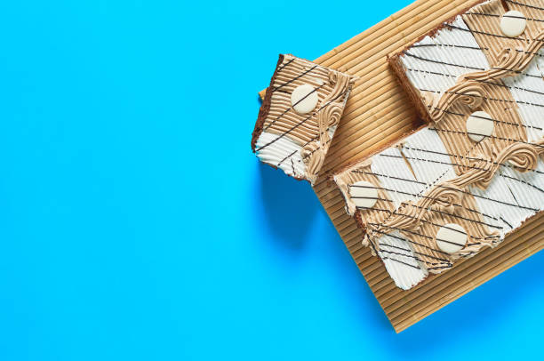 istock Sliced checkered rectangular cake on bamboo mat lies on blue table on party. Celebration concept. Space for text. Top view 1200594421