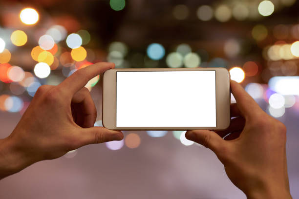 Hands holding a mobile phone with a blank display, unsharp colorful lights in the background