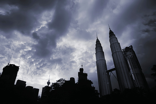 City silhouette with high buildings and skyscrapers under dramatic clouds in Kuala Lumpur, Malaysia, Asia.