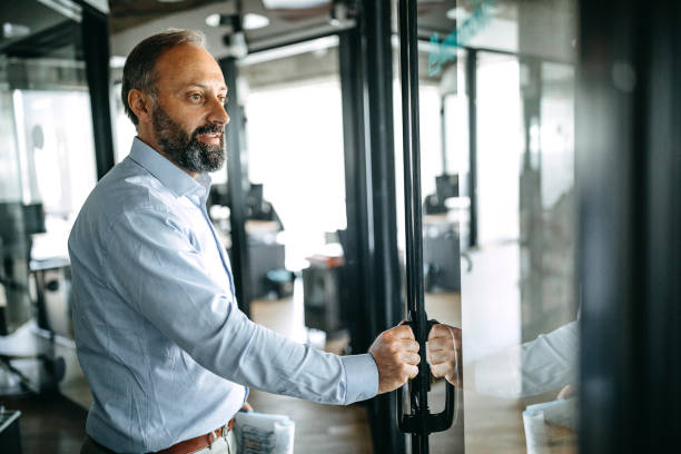 Businessman with report at doorway in office Side view of a businessman holding financial report at doorway opening door in office office leave stock pictures, royalty-free photos & images