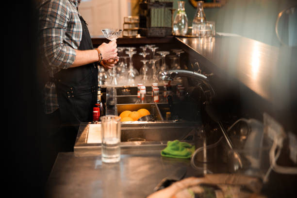 istock Young male bartender holding glass in his hands 1200606598