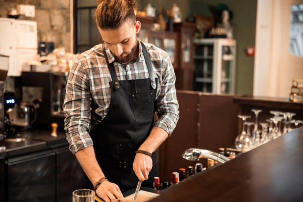 istock Experienced barman is slicing fruit for cocktail 1200606654