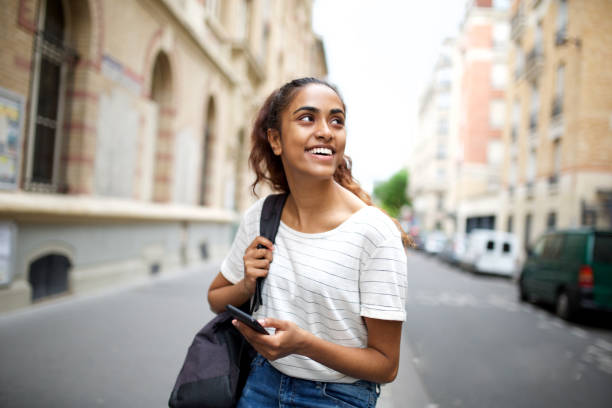 istock college student sitting outside with mobile phone and looking away 1200610312