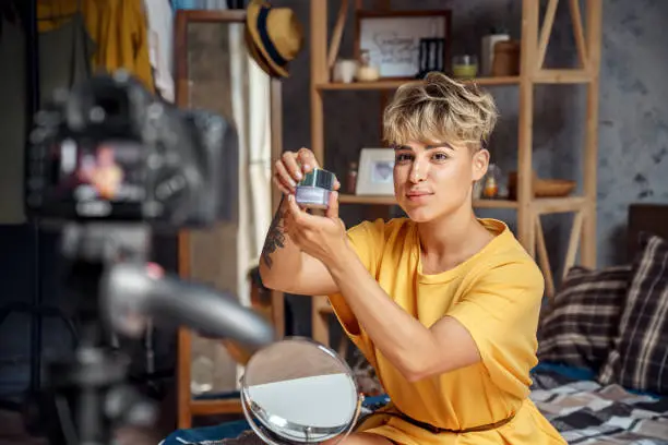 Photo of Young adult vlogger choosing cosmetics for makeup