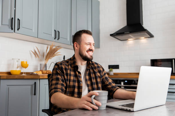 istock Guy with a cup of coffee is working on a laptop. 1200610765