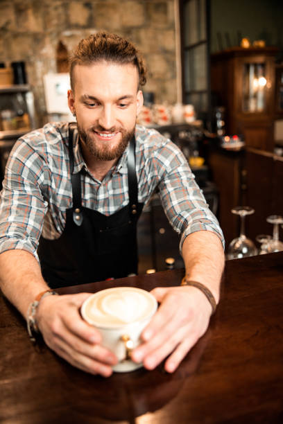 istock Smiling young barista making latte in cafeteria 1200613780