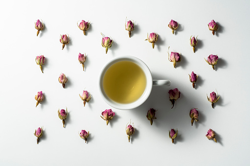 Rose tea and rose buds flat lay on white background