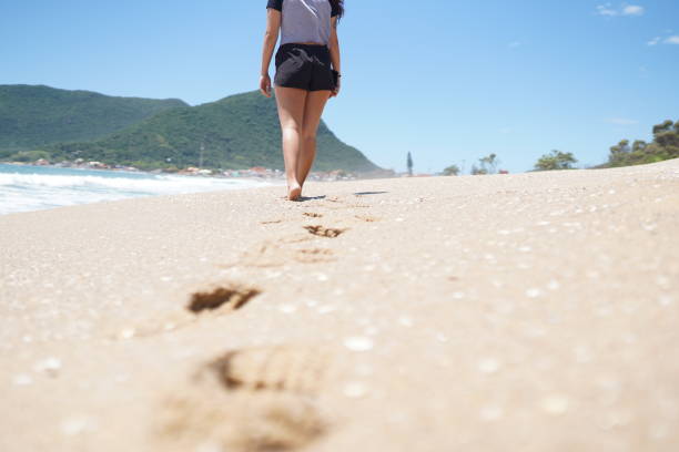 Aerial photo of people walking on Tallow Beach, Byron Bay, NSW north coast during the time of the global pandemic, practising safe social distancing. Waves are breaking in the shallow water at the edge of this pristine coastal beach on a sunny day