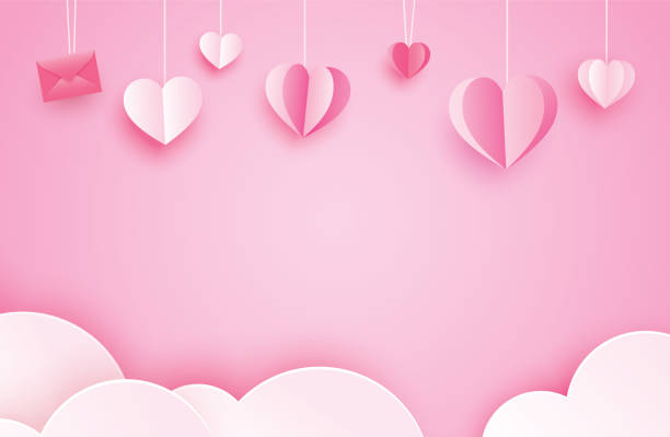 istock Happy valentines day greeting cards with paper hearts hanging on pink pastel background. 1200631300