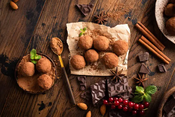 Homemade vegan chocolate truffles with raw cocoa powder on a wooden table background, top view