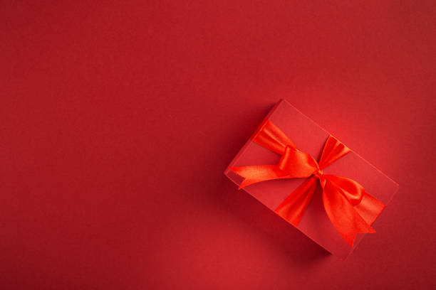 istock Valentine's day or mother's day concept. Red gift box with bow on red background top view 1200650143
