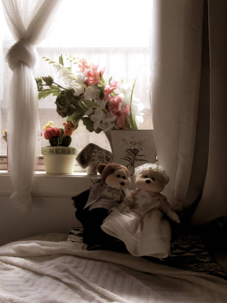 A pair of male and female stuffed animals in wedding dress arranged nicely under a bedroom window. Suitable to illustrate the concept or marriage life, honeymoon, wedding gift or couple's retreat