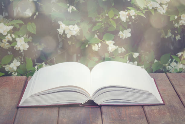istock Empty opened book on aged wooden table on fresh jasmine flowers background. Selectve focus. 1200653397