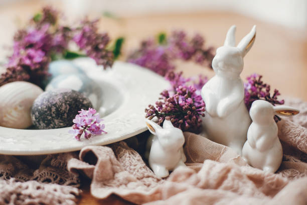 istock Happy Easter. Rustic composition of natural dyed easter eggs, lilac flowers and bunny rabbits on linen fabric on wooden table. White ceramic bunny and spring flowers. 1200654020