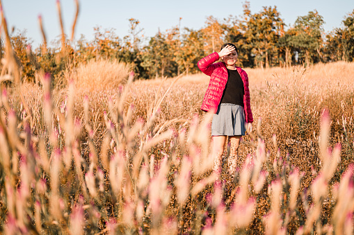 A girl walking on a mountain of brown grass