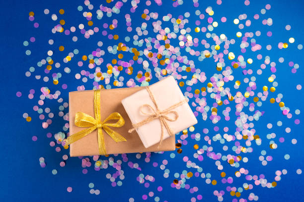 Two boxes with gift on blue background with confetti. stock photo