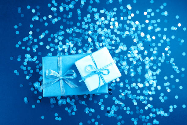 Two boxes with gift on blue background with confetti. stock photo