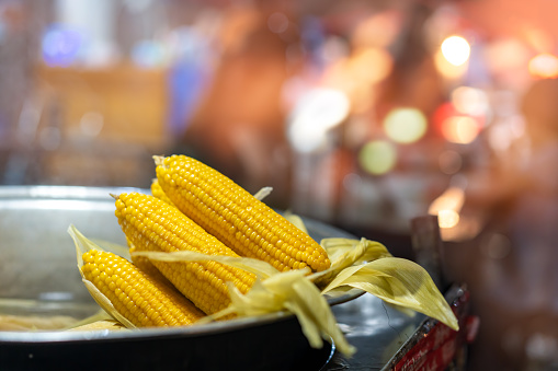 Freshly steamed corn in a metal bowl for sale on the street market in small town, China