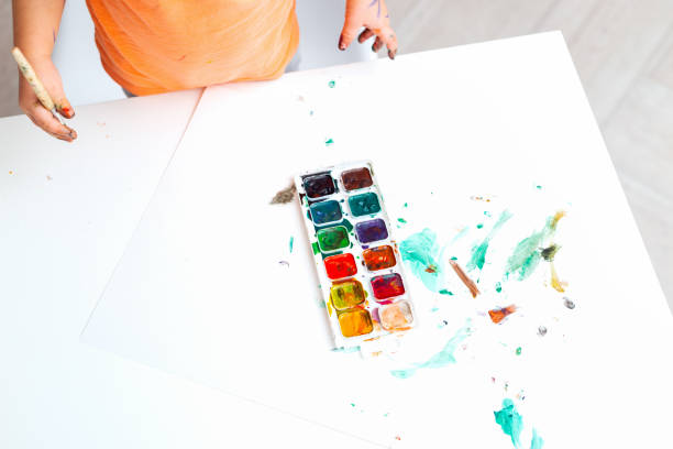 赤ちゃんの手は、ブラシと水彩画の塗料を保持します。ベビーアート。スペースをコピーします。フラットレイ - child art childs drawing painted image ストックフォトと画像