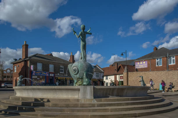 View of a round stone fountain with stairs around and a kid and otter sculptures on Braintree city downtown Braintree, England / United Kingdom - 04 17 2014: View of a round stone fountain with stairs around and a kid and otter sculptures on Braintree city downtown braintree essex photos stock pictures, royalty-free photos & images