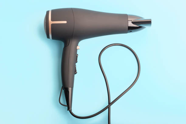 czarna suszarka do włosów na niebieskim tle z bliska widok z góry. - hair dryer single object plastic black zdjęcia i obrazy z banku zdjęć