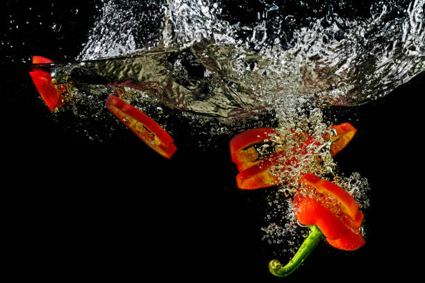 istock Red fresh paprika slices splash in water on a black background. 1200666344