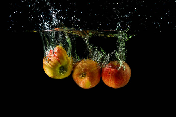 istock Three apples splashing into water on black background. 1200666426