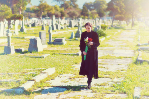 istock Young woman carrying flowers through old cemetery 1200669018