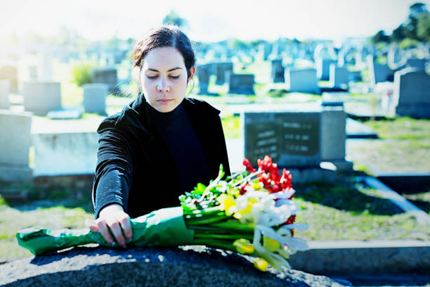 istock Mourning woman placing flowers on cemetery grave 1200671282