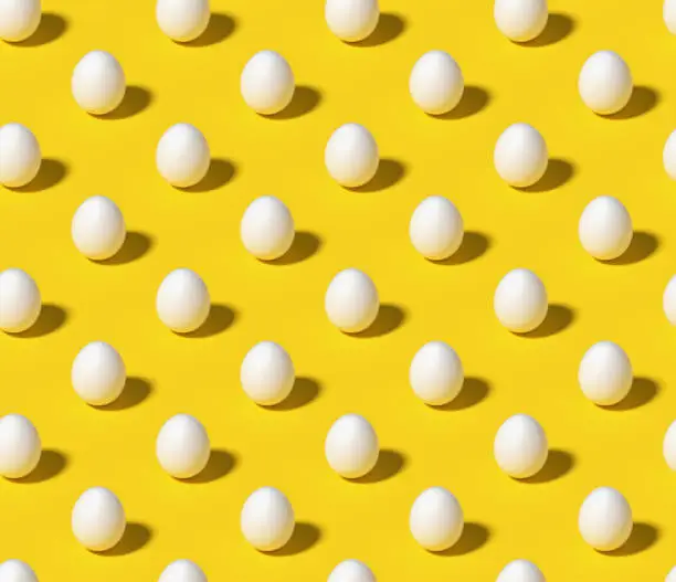 Photo of White eggs on bright yellow seamless isometric background
