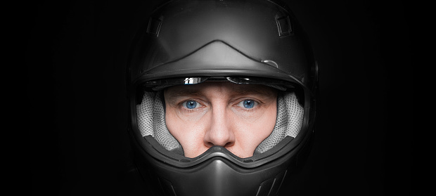 Man in motorcyclist helmet on dark studio background. Closeup. Protection concept.