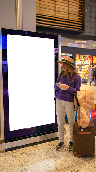 Young woman looking white billboards at the airport