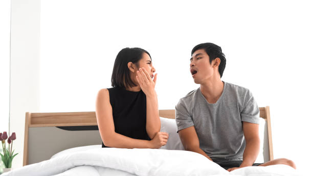 young couple waking up in bed in the morning young couple waking up in bed in the morning bad breath couple stock pictures, royalty-free photos & images