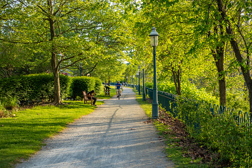 Pittsburgh, Pennsylvania, USA. May 7, 2019. A man is riding a bike under green trees and a girl is sitting on a bench. A place for relaxation or activities.