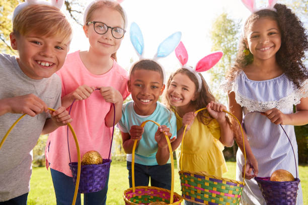 verticale de cinq enfants utilisant des oreilles de lapin sur la chasse d'oeuf de pâques dans le jardin - people in a row in a row human face smiling photos et images de collection