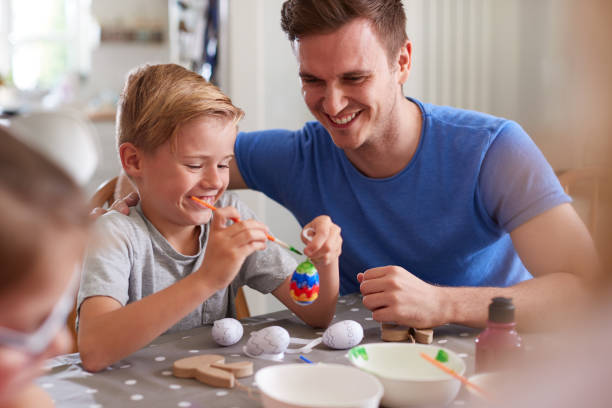 istock Father With Children Sitting At Table Decorating Eggs For Easter At Home 1200677893