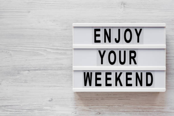 istock 'Enjoy your weekend' words on a modern board on a white wooden background, top view. Overhead, from above, flat lay. Copy space. 1200679207