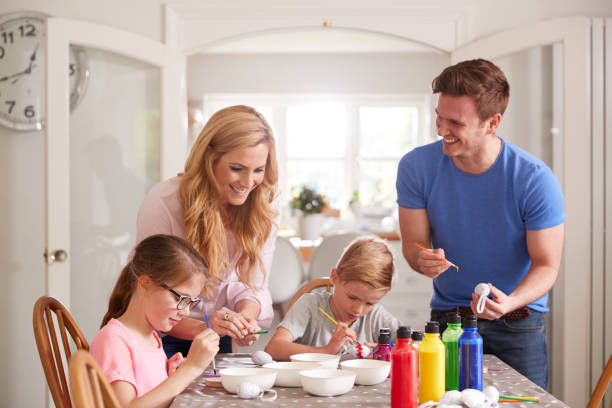 istock Parents With Children Sitting At Table Decorating Eggs For Easter At Home 1200679528