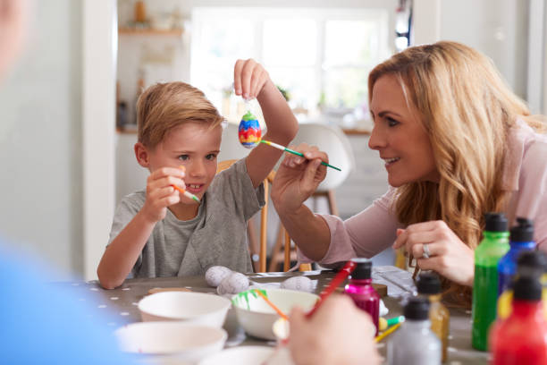 istock Mother With Son Sitting At Table Decorating Eggs For Easter At Home 1200679543