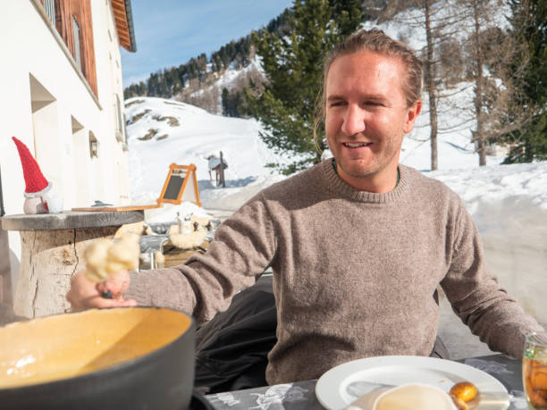 istock Young man eating cheese fondue in chalet 1200682040