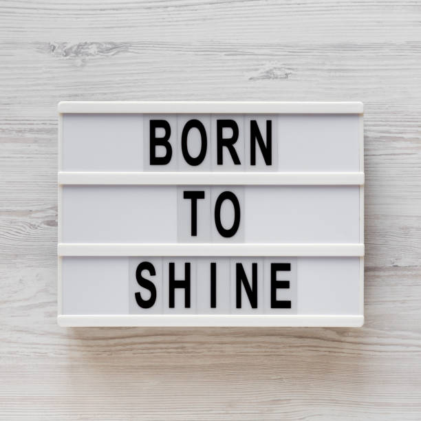 istock 'Born to shine' words on a lightbox on a white wooden surface, top view. Overhead, from above, flat lay. Close-up. 1200683585