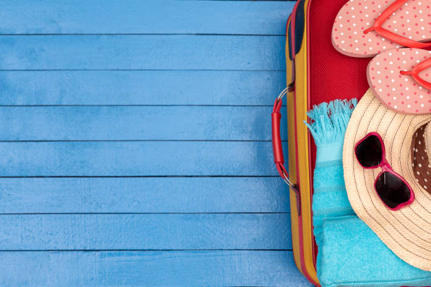 istock Flip-flops, hat, suitcase, beach towels and sunglasses on wooden table. 1200683848