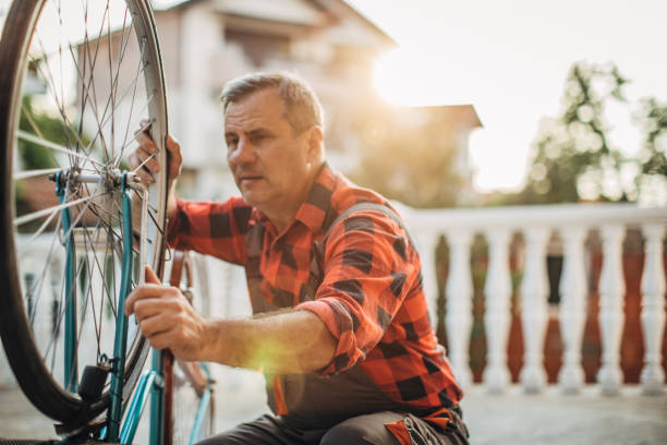 istock Senior man repairing a bicycle in front yard alone 1200685887