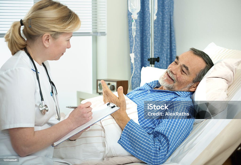 in hospital doctor or nurse talking to a senior patient lying in bed  in hospital. Adult Stock Photo