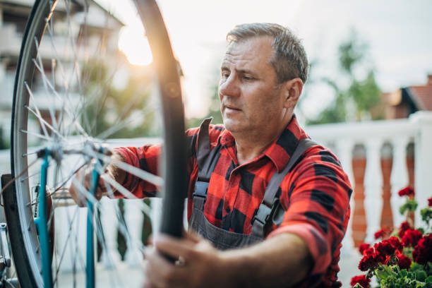 istock Senior man repairing a bicycle in front yard alone 1200688434
