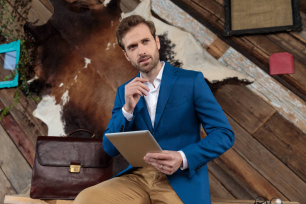 istock Thoughtful businessman holding his tablet and looking away 1200688580