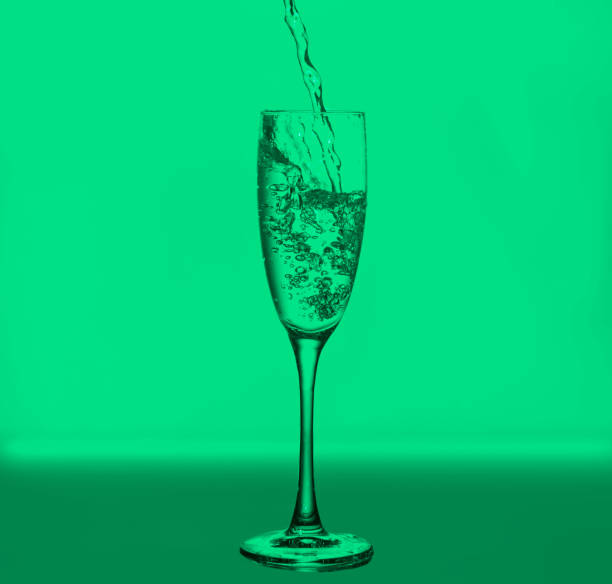 wineglass with bubbles and drops on green background