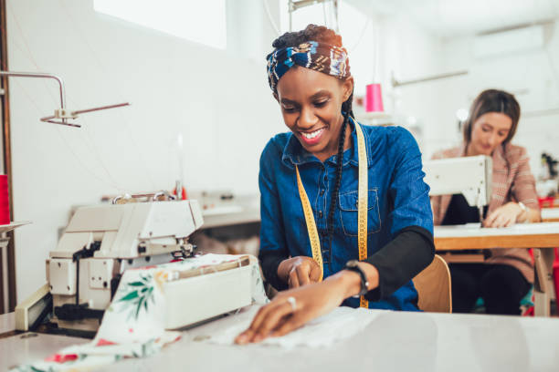 Dressmaker woman working with sewing machine Young african textile worker sewing on production line. Dressmaker woman working with sewing machine tailor photos stock pictures, royalty-free photos & images